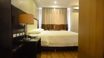 Habitació d'hotel amb un llit, una taula de nit amb una làmpada, un telèfon i un aire condicionat fixat a la paret.