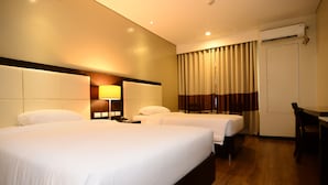 Ein Hotelzimmer mit zwei Betten, einem Schreibtisch, einer Lampe und einer Klimaanlage.