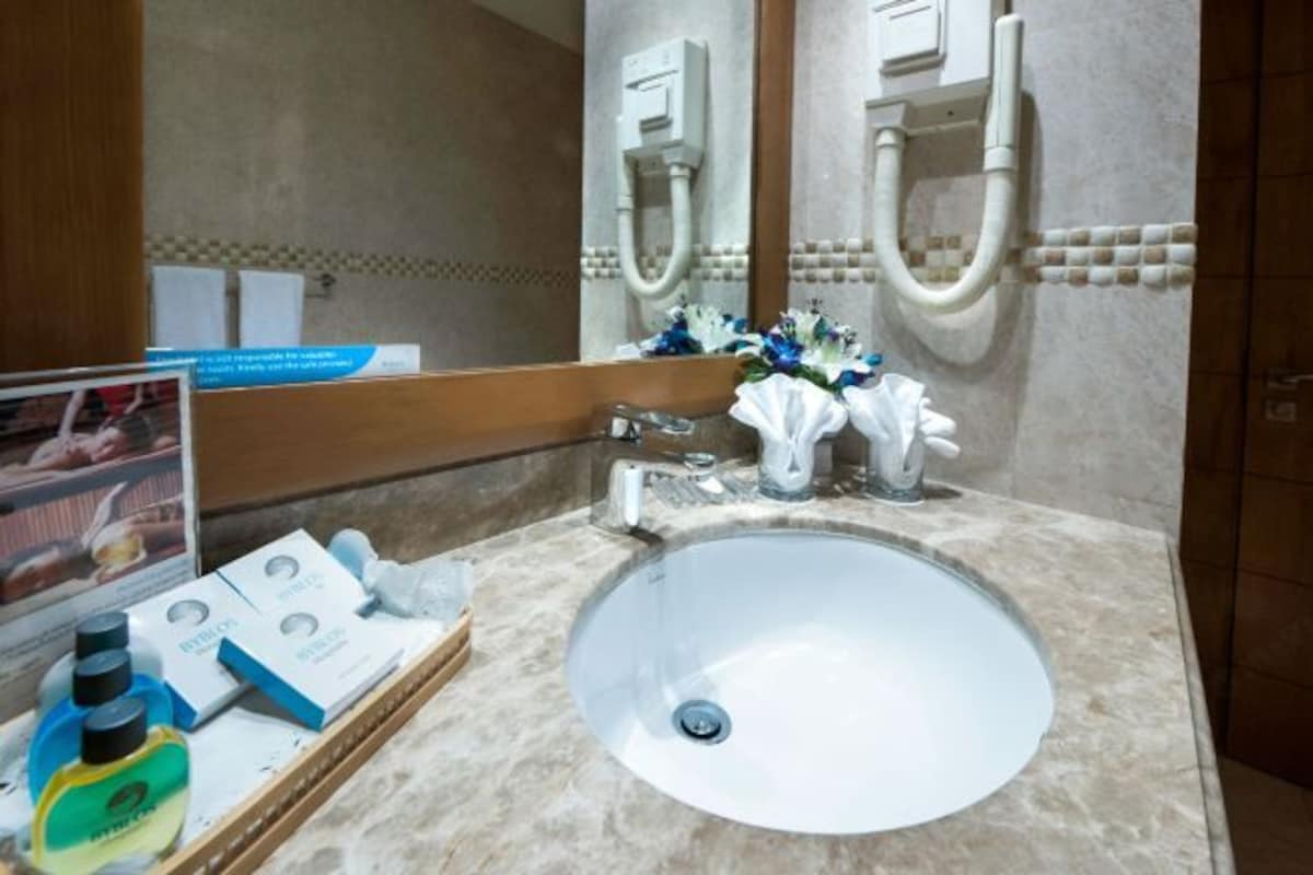 A bathroom with a round sink, a mirror, and a towel rack. There are toiletries on the counter.