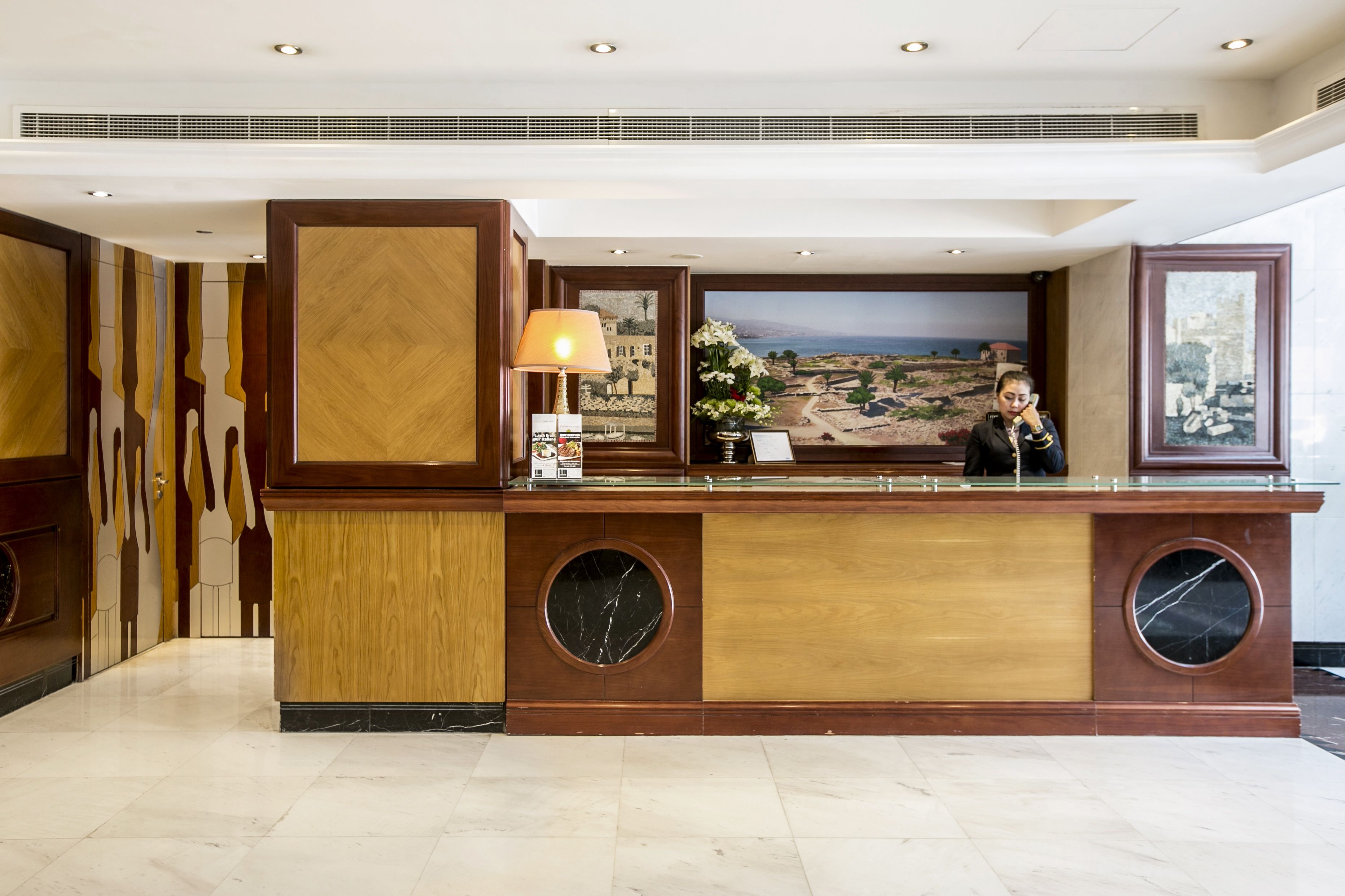 A reception desk with a large window, a lamp, and a view of a landscape.