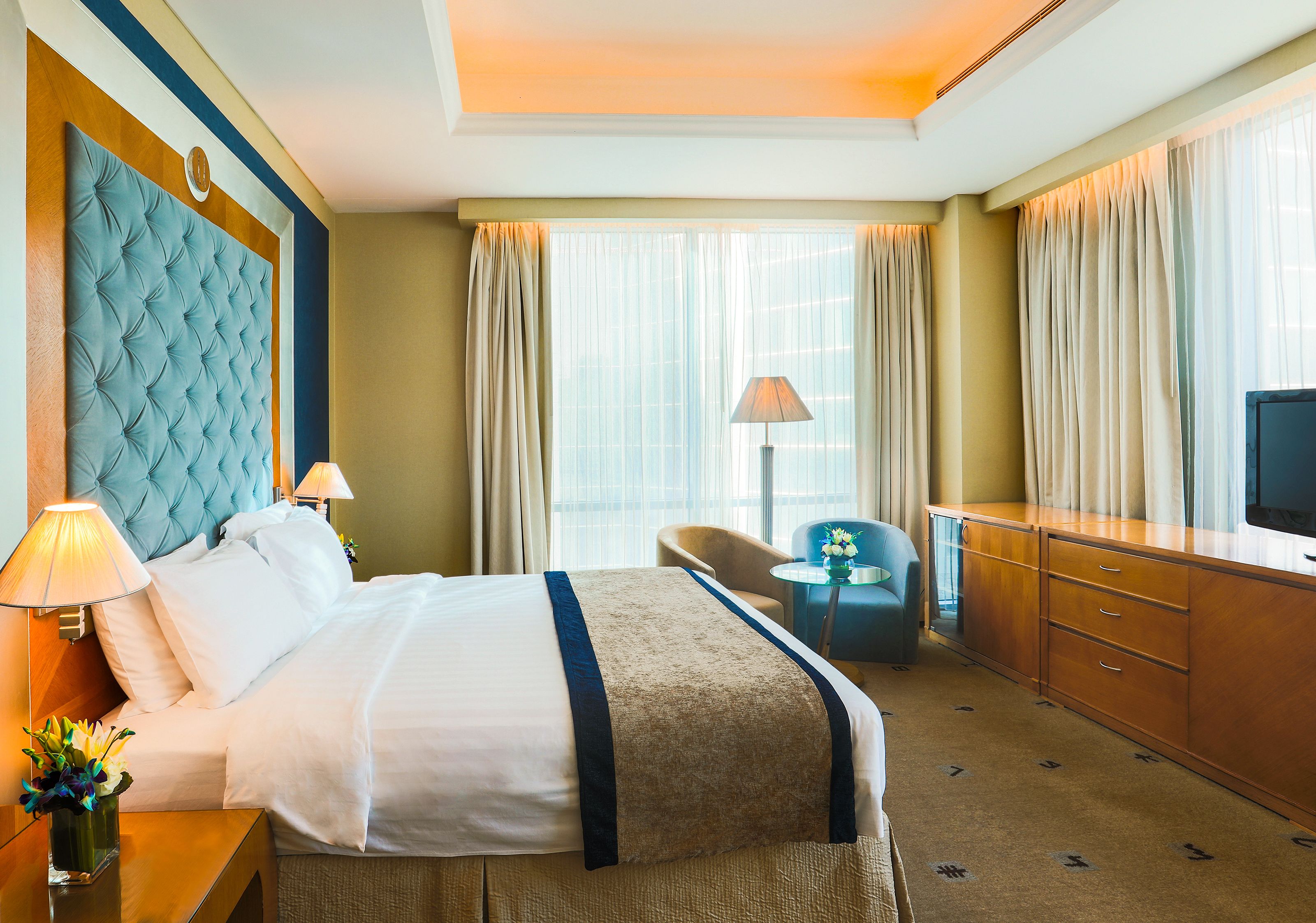 A hotel room with a large bed, a desk, a chair, and a TV.