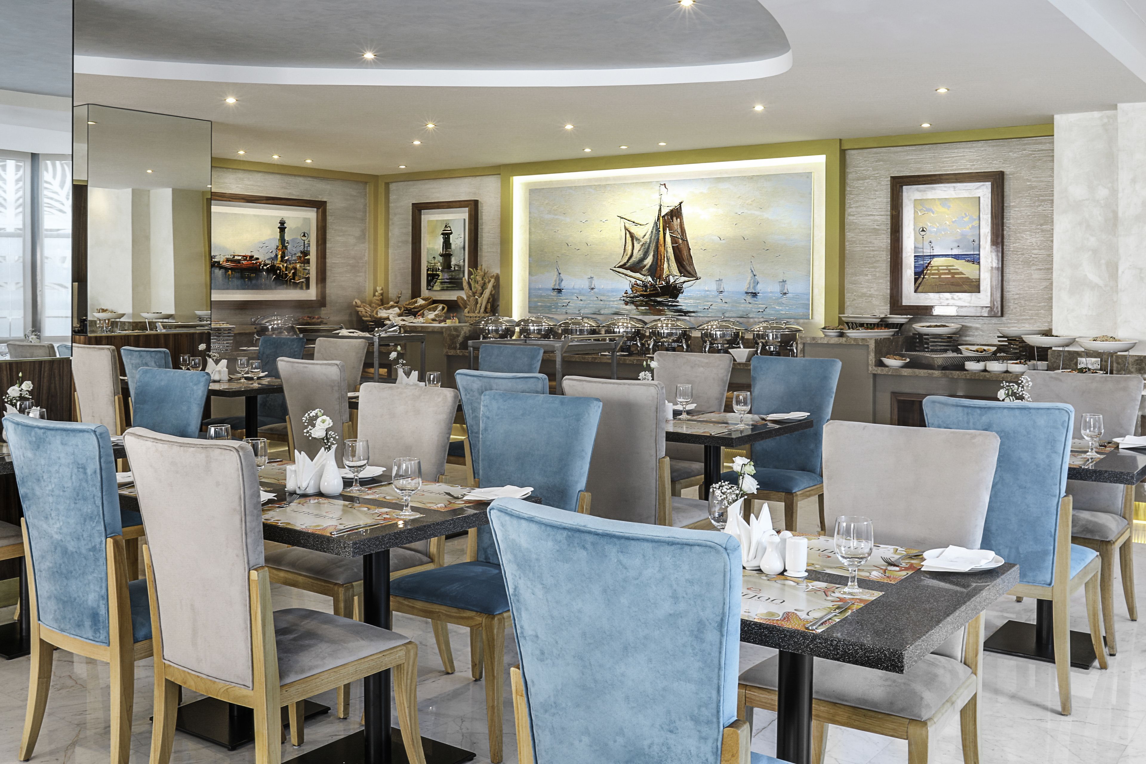 Ein Restaurant mit mehreren Tischen und Stühlen, das Kunstwerken an den Wänden und einem modernen Interieur zeigt.