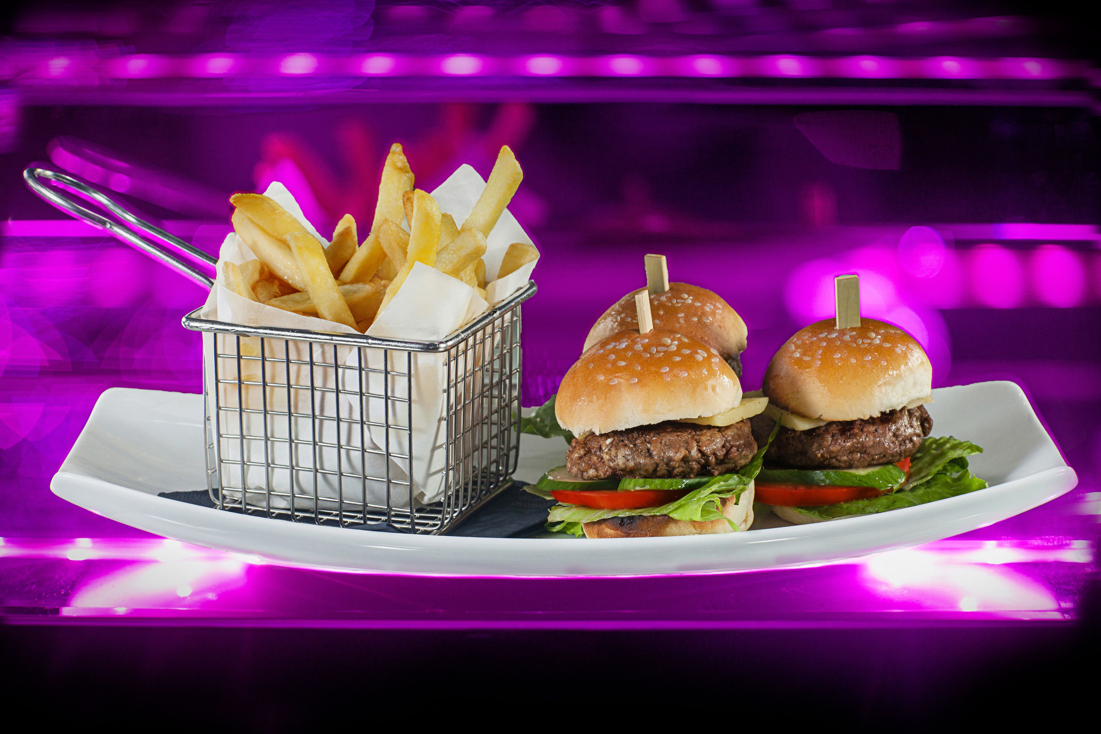 A plate with two burgers and a basket of fries.
