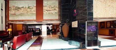 A spacious lobby with a marble floor, red seating, a large vase, and a cityscape mural on the wall.
