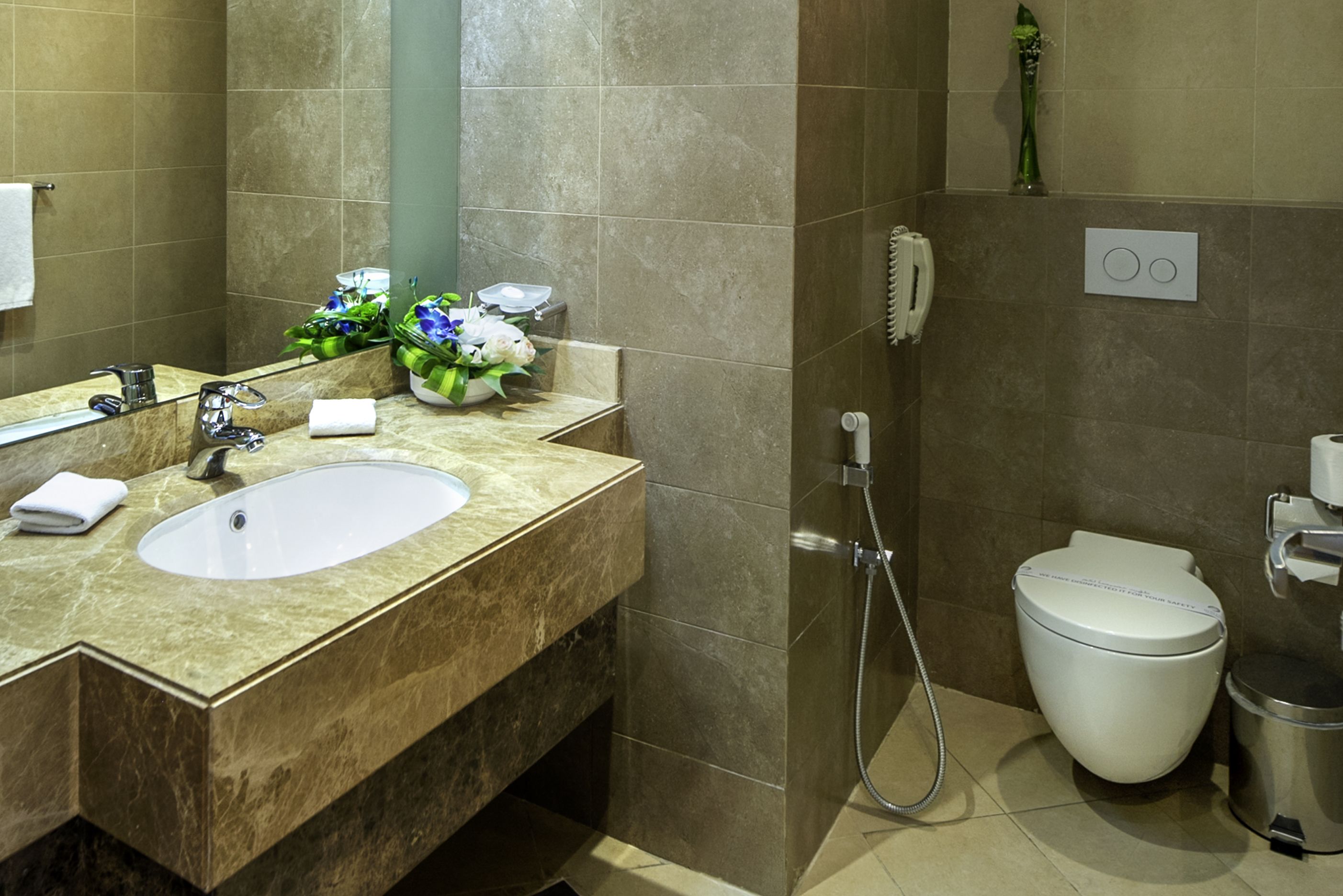 A bathroom with a marble sink, a toilet, and a shower.
