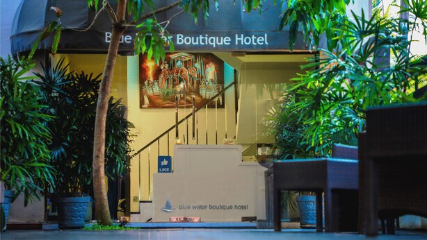 The exterior of the Blue Water Boutique Hotel with a sign, potted plants, and a staircase leading to the entrance. - Blue Water Boutique Hotel (Negombo)