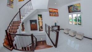 A spacious interior with a wooden staircase, white walls, and artwork. - Blue Water Boutique Hotel (Negombo)
