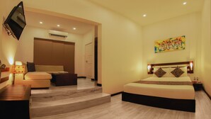 A hotel room with a bed, a sofa, a TV, and a painting on the wall. - Blue Water Boutique Hotel (Negombo)