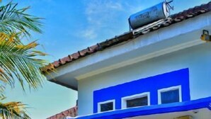 A two-story house with a blue and white exterior, a covered porch with a table and chairs, and a stone pillar. - Seulawah Resort And Cafe (Batu)