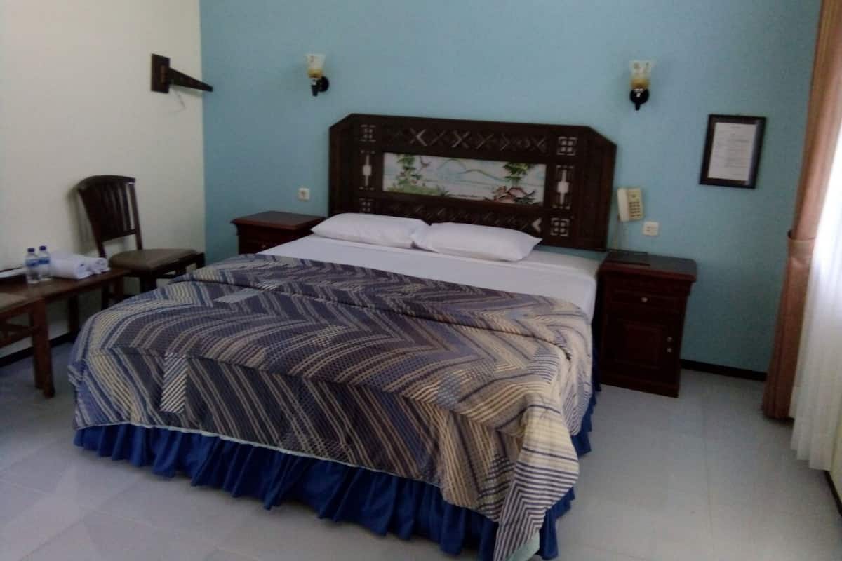 A hotel room with a bed, bedside tables, a chair, and a desk.