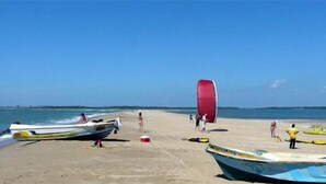 Una playa con barcos y un paracaídas.