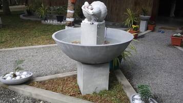 Un jardin agrémenté d’un élément aquatique central, entouré de plantes en pot et bordé d’un chemin de gravier.