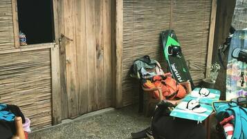 Un petit espace extérieur clos, doté d’une porte en bois, d’une table, ainsi que de divers sacs et équipements.