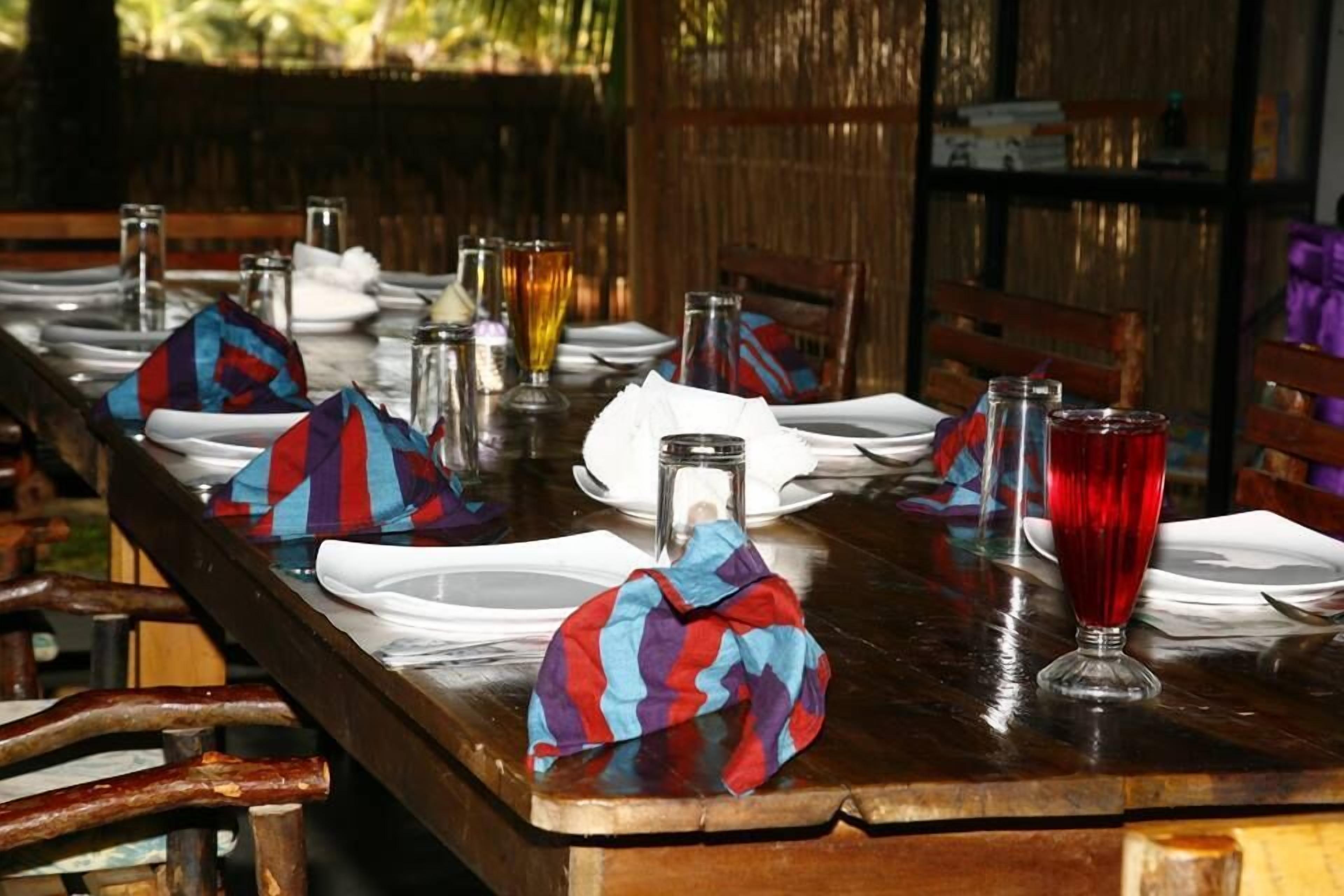 Une table à manger dressée avec des assiettes, des verres et des serviettes, entourée de chaises.