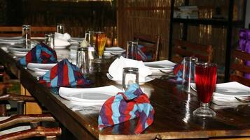 Une table à manger dressée avec des assiettes, des verres et des serviettes, entourée de chaises.