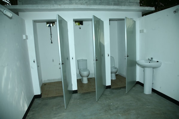 Un baño con cuatro inodoros y un lavamanos.