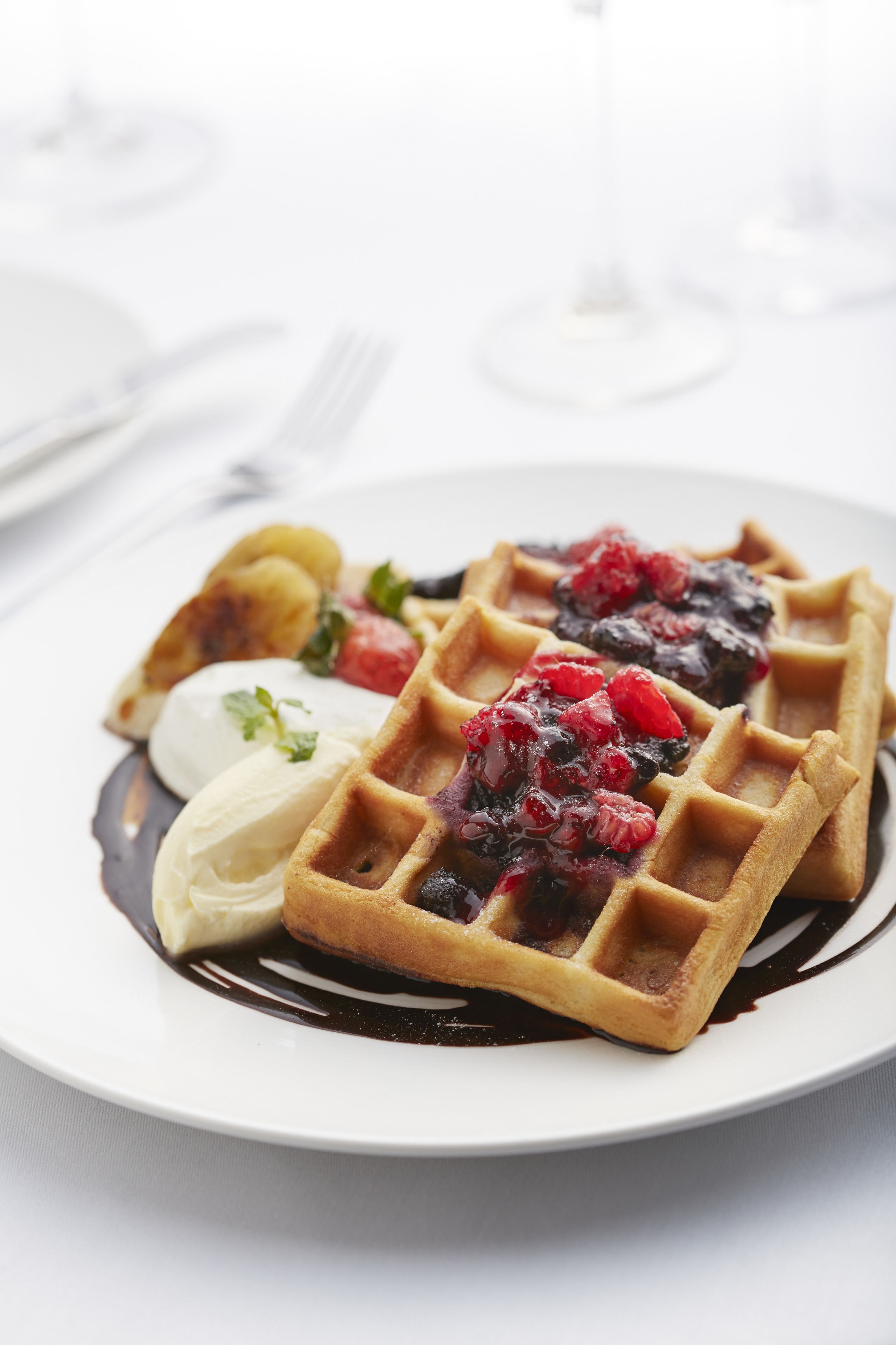 A plate with a Belgian waffle topped with berries and a scoop of ice cream.