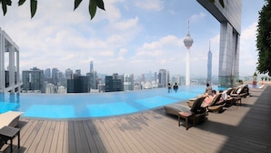 A rooftop infinity pool with lounge chairs, a wooden deck, and a city skyline view. - THE FACE Suites Hotel (Kuala Lumpur)