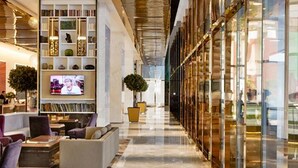 A modern hotel lobby with a long corridor, seating areas, and a television. - THE FACE Suites Hotel (Kuala Lumpur)