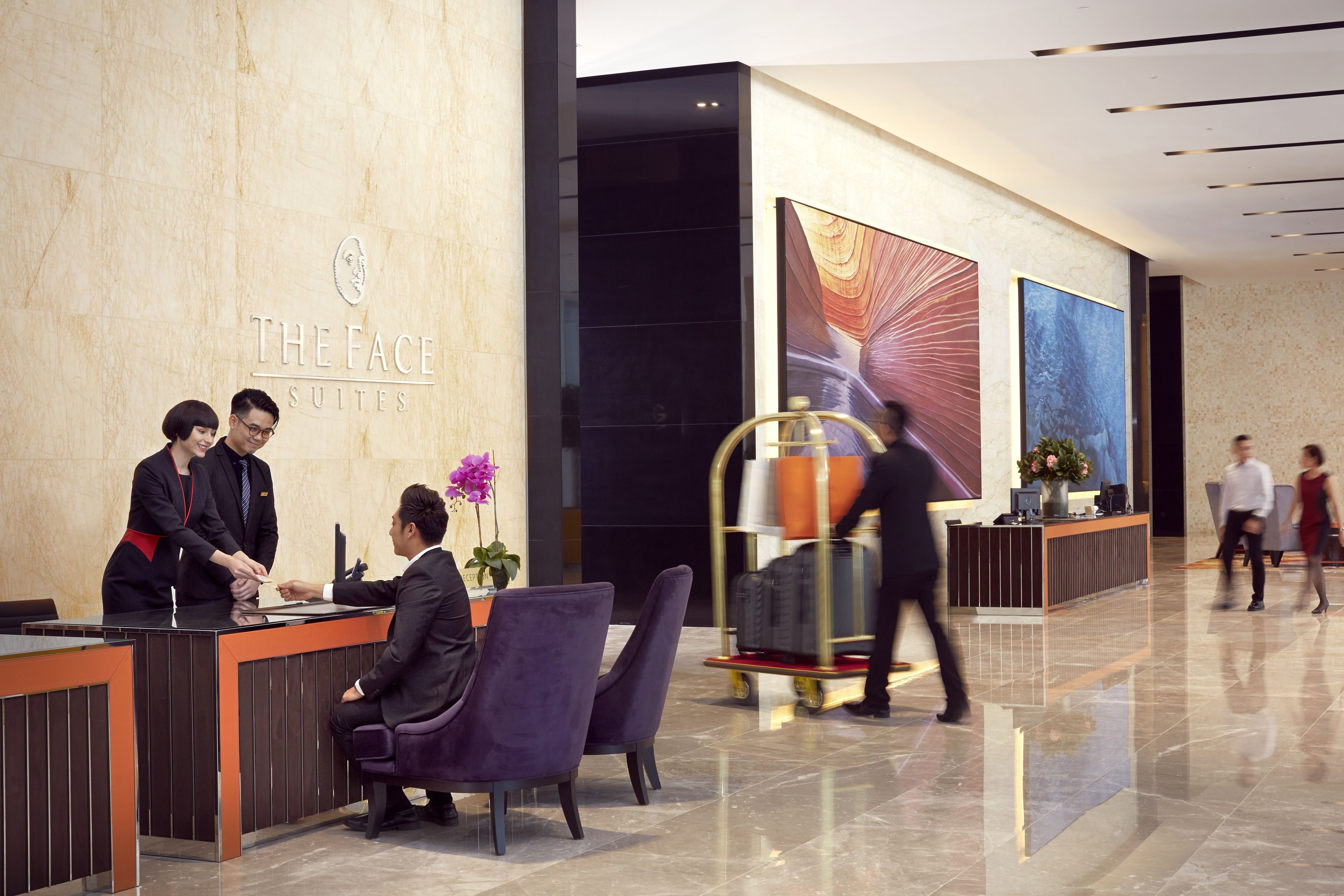 A hotel reception area with a marble wall, a reception desk, and a large abstract painting.