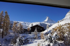 A snow-covered mountain landscape with a chalet and a prominent peak in the background. - Apartments Zermatt Paradies (Zermatt)