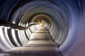 A tunnel with a central walkway and a metal railing on the left. - Apartments Zermatt Paradies (Zermatt)
