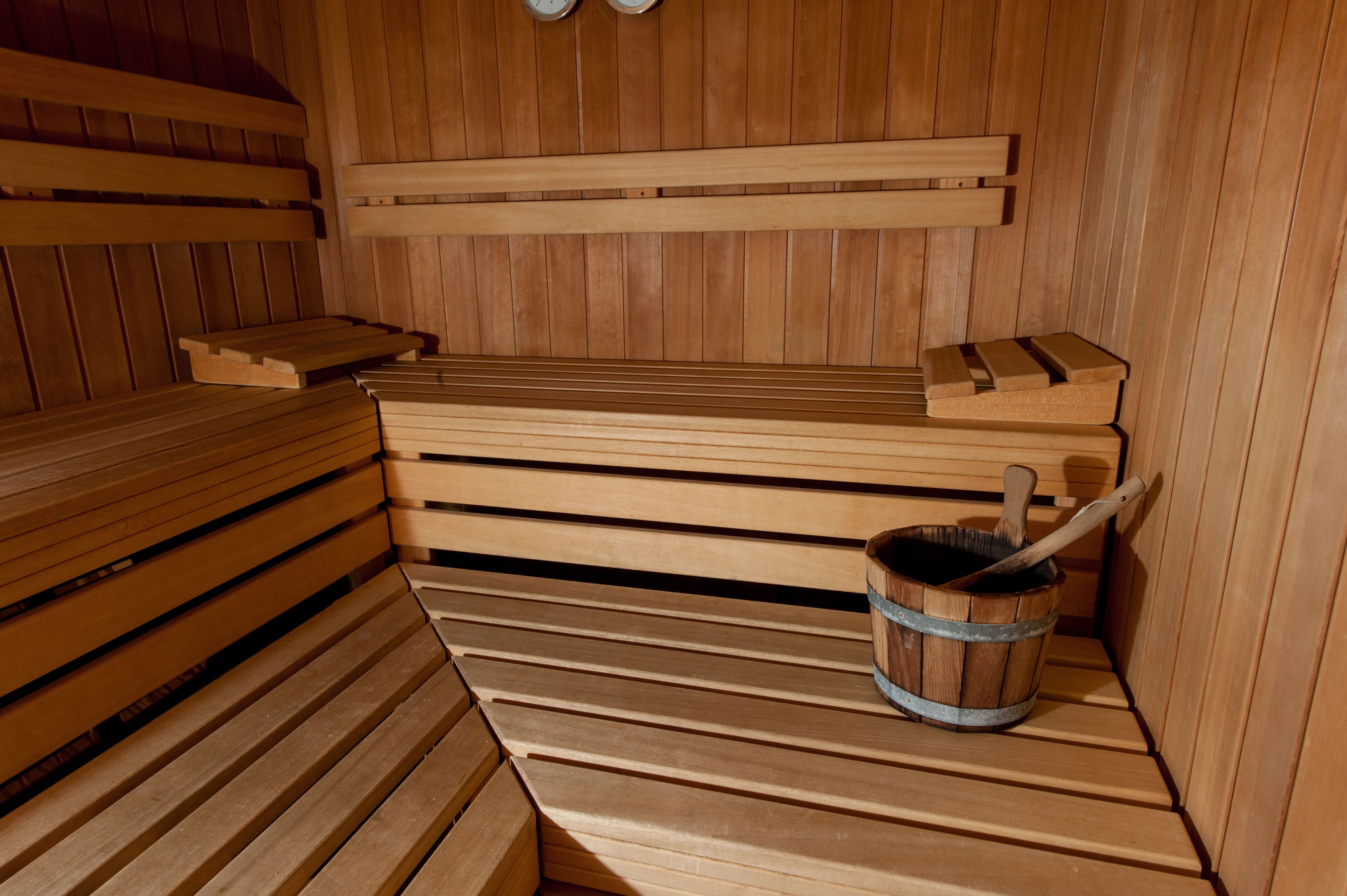 A wooden sauna with benches and a bucket.