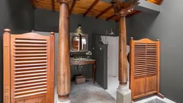 A bathroom with wooden shutters, a mirror, and a sink.