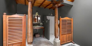 A bathroom with wooden shutters, a mirror, and a sink.