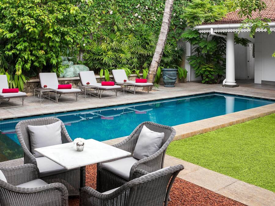 A poolside area with lounge chairs, a table, and a small garden.