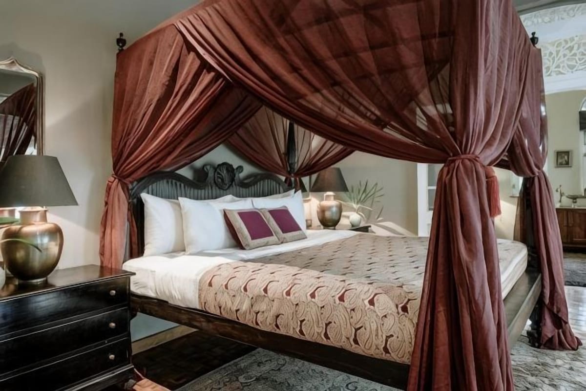 A four-poster canopy bed with a headboard, bedside tables, and lamps.