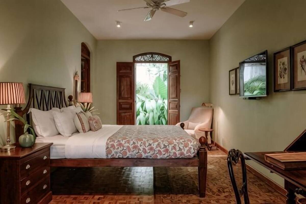 Ein Schlafzimmer mit Bett, Schreibtisch, Stuhl, Lampe und Deckenventilator.