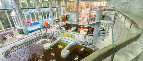 Una piscina interior de varios niveles con diferentes zonas de estar y un elemento central de agua.