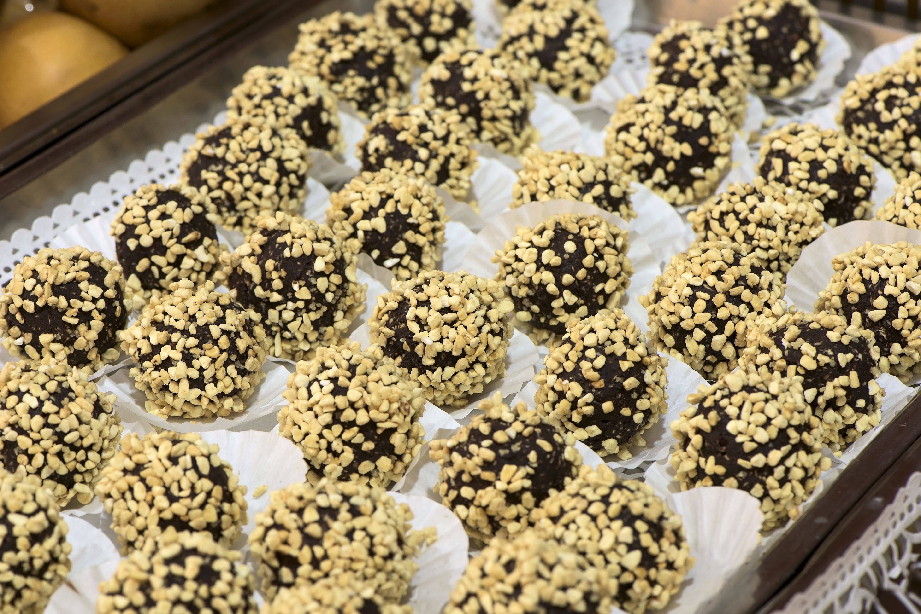 Una bandeja de trufas de chocolate cubiertas de nueces picadas.