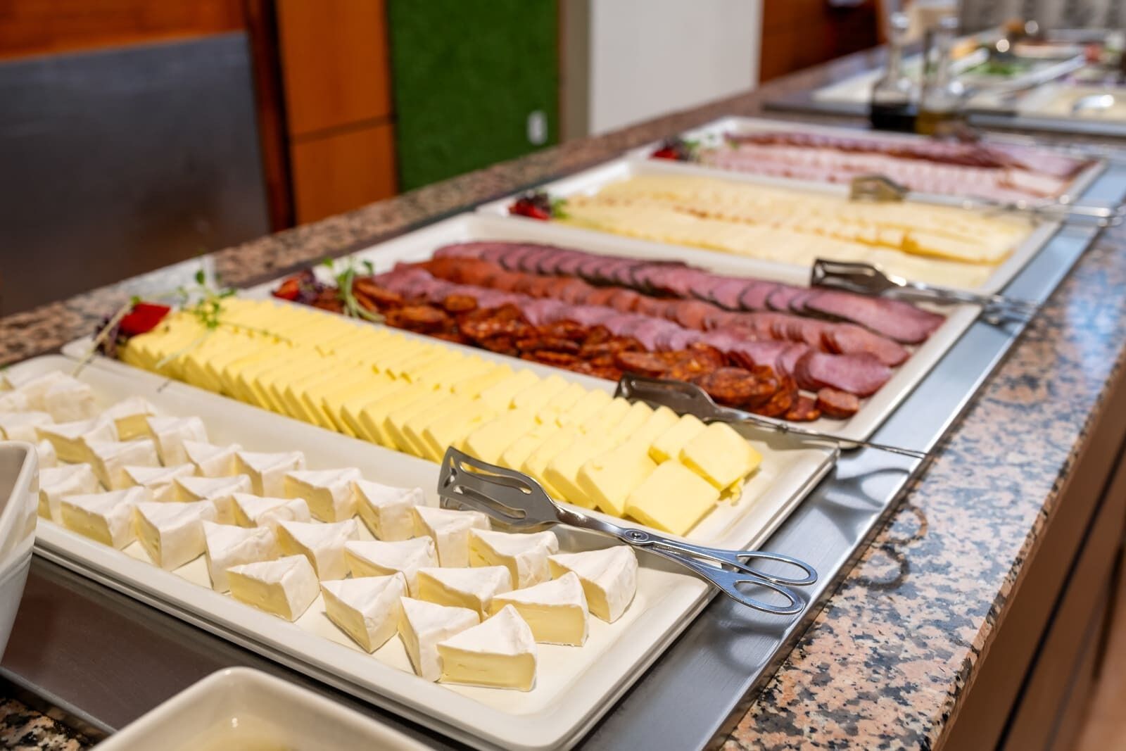 A buffet with various cheeses and meats.
