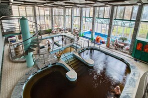 A swimming pool area with multiple levels, stairs, and seating areas. - Hotel Barátság Hajdúszoboszló Superior (Hajduszoboszlo)