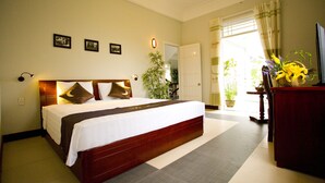 Une chambre d’hôtel avec un grand lit, un bureau et une plante en pot.