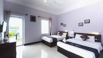 A hotel room with two beds, a desk, and a window with curtains.