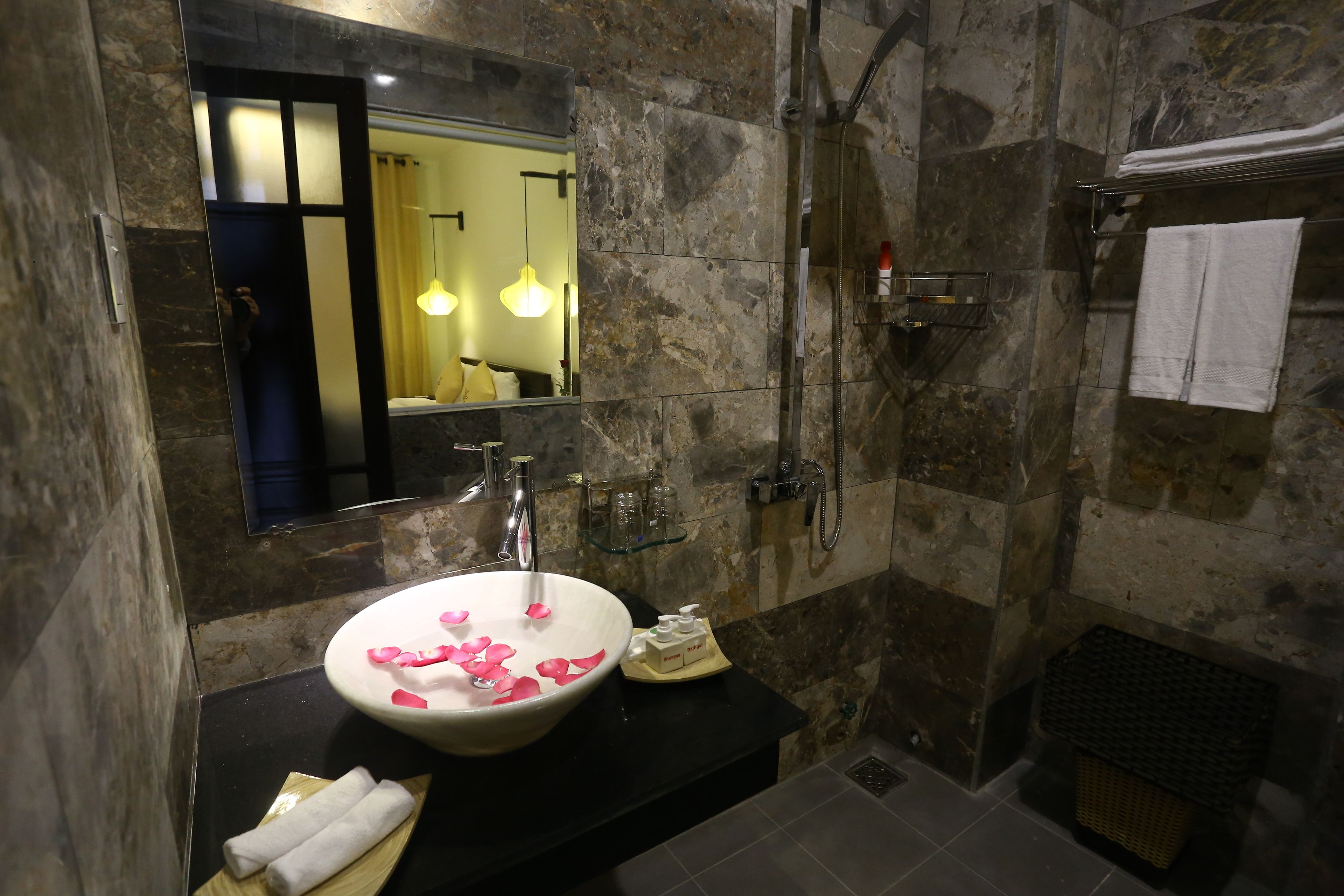 A bathroom with a marble sink, a mirror, a shower, and a towel rack.