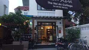 A café named "Nha Xua The Hoi An Cottage" with a signboard, a motorcycle parked outside, and a bicycle. - Hoi An Cottage Villa (Da Nang)