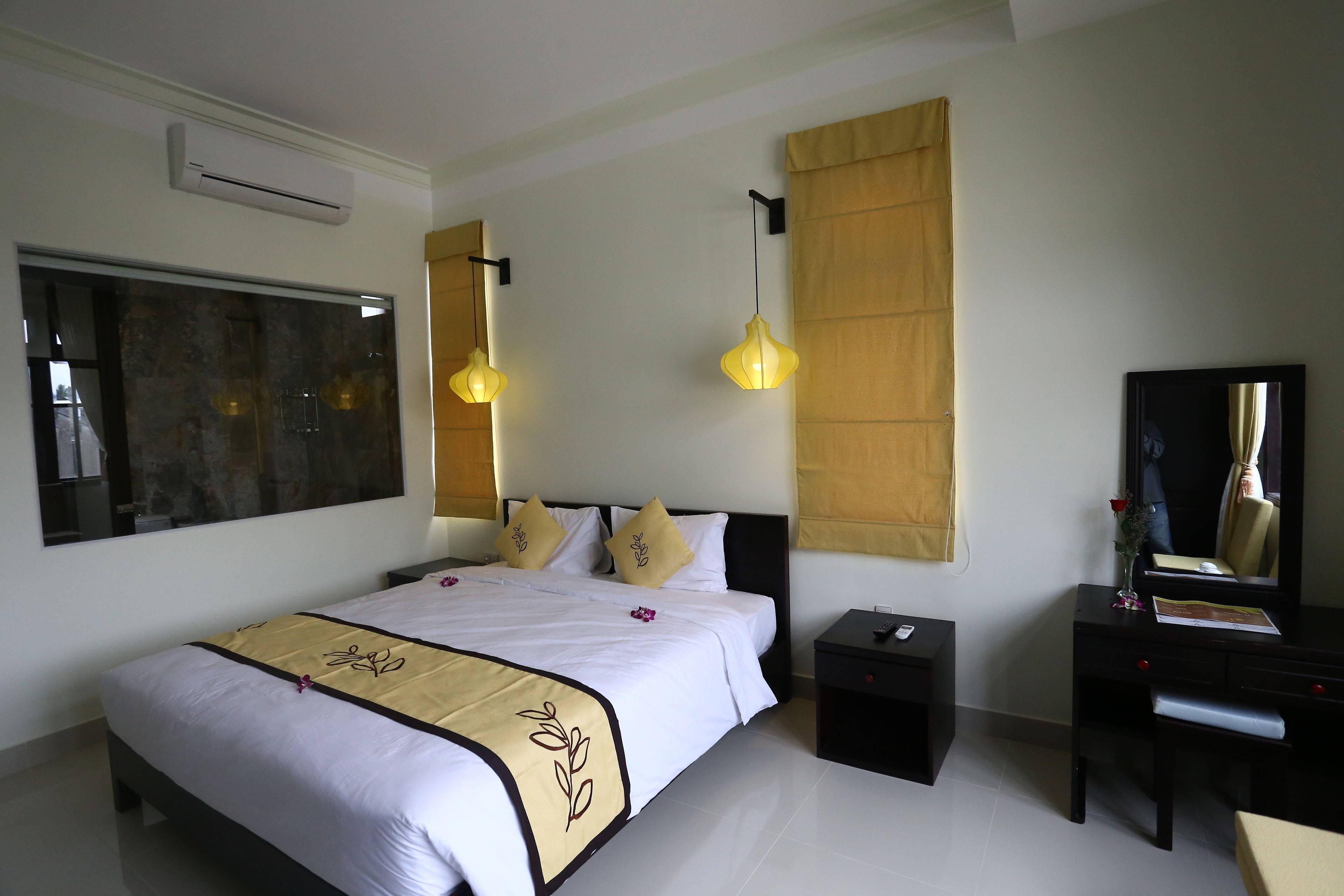 A hotel room with a large bed, bedside tables, a desk, and a mirror.