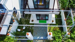 Una casa moderna con tetto rosso, un balcone e un piccolo giardino con piante in vaso.