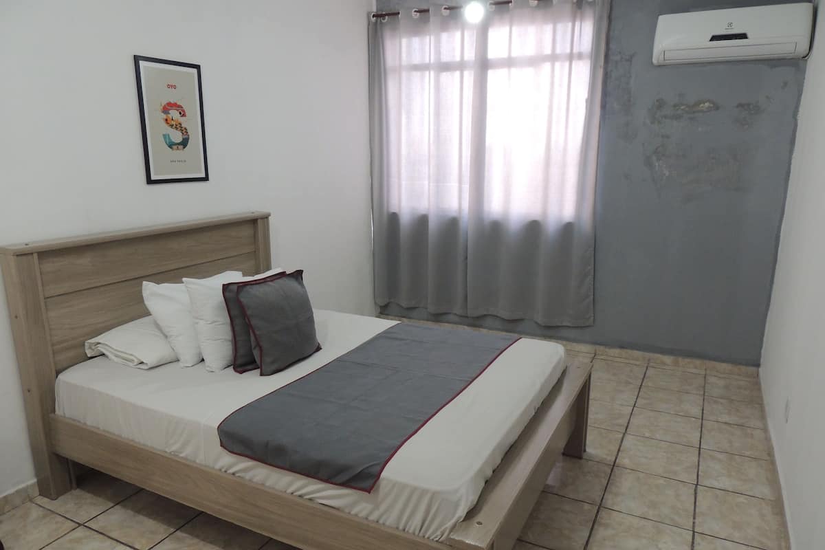 A neatly made bed with white and gray bedding, a wooden headboard, and a gray throw blanket.