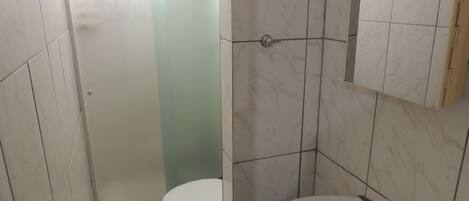 Un baño con inodoro, lavamanos y cabina de ducha.