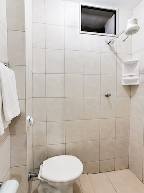 Bathroom features a shower area, toilet, and tile walls.