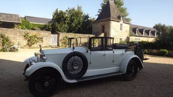 A vintage white convertible car parked on a gravel surface.