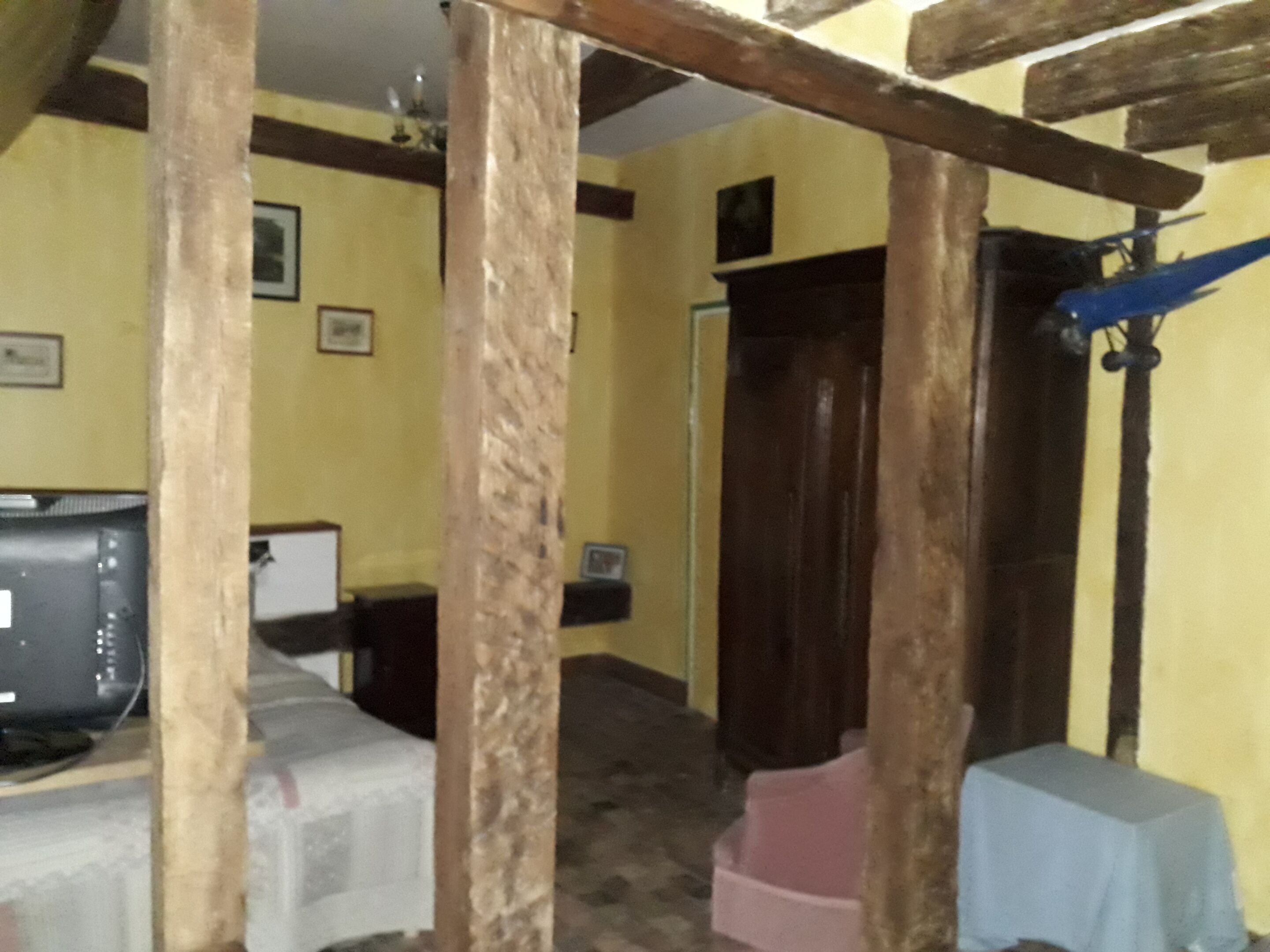 A room with a wooden ceiling, a television, a small table, and a door.