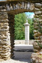Un arco de piedra que da a un pilar de piedra con una valla al fondo.
