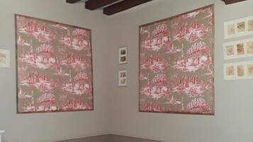 A room with two beds, wooden beams on the ceiling, and large patterned wall art.