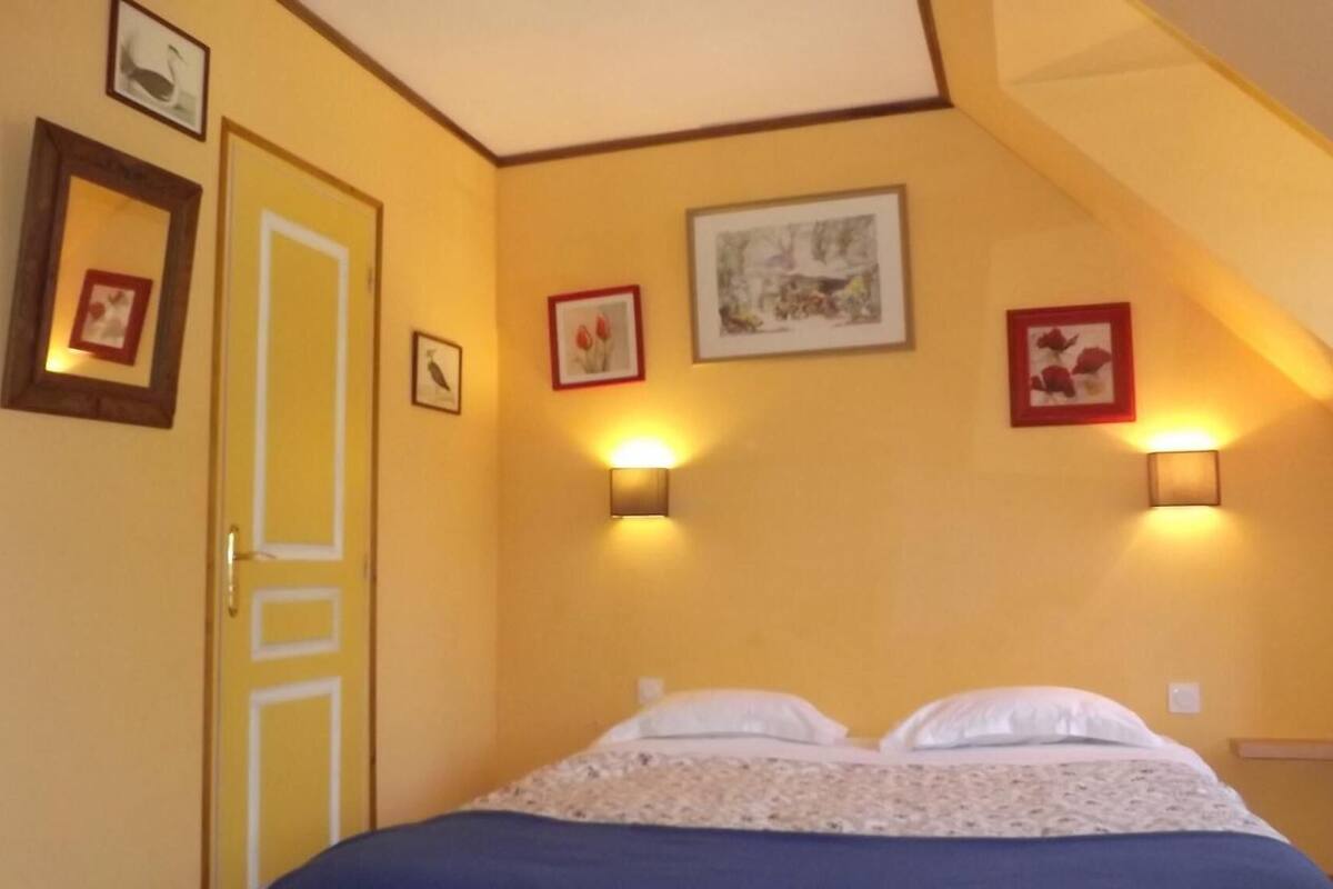 A bedroom with a bed, two wall-mounted lights, and a door.
